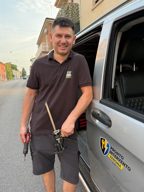 Il tecnico di Pronto Intervento Verona accanto al furgone attrezzato, con gli attrezzi in mano: è lui che risponde al telefono e che viene sul posto