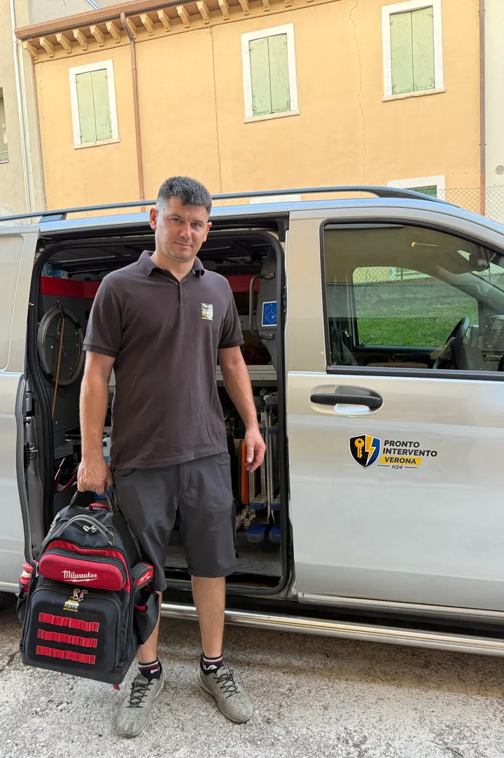 Il tecnico di Pronto Intervento Verona con la borsa degli attrezzi, davanti al furgone attrezzato con il logo: fabbro, elettricista e idraulico, disponibile 24 ore su 24